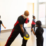 MMA teacher at new settlement teaching kid how to punch