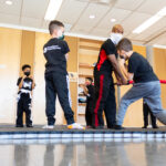 MMA teacher training kids on mat with foam sword