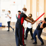 MMA teacher training kids with foam sword at new settlement