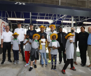 Group photo of children, Bronx community leaders and Yankees players in front of a hydroponic garden.