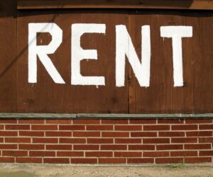 Rent is written in white paint on the outside of a building