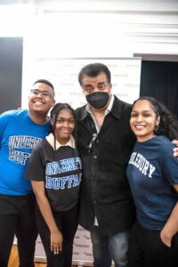 Students and college advisor smiling next to scientist Neil Degrasse Tyson