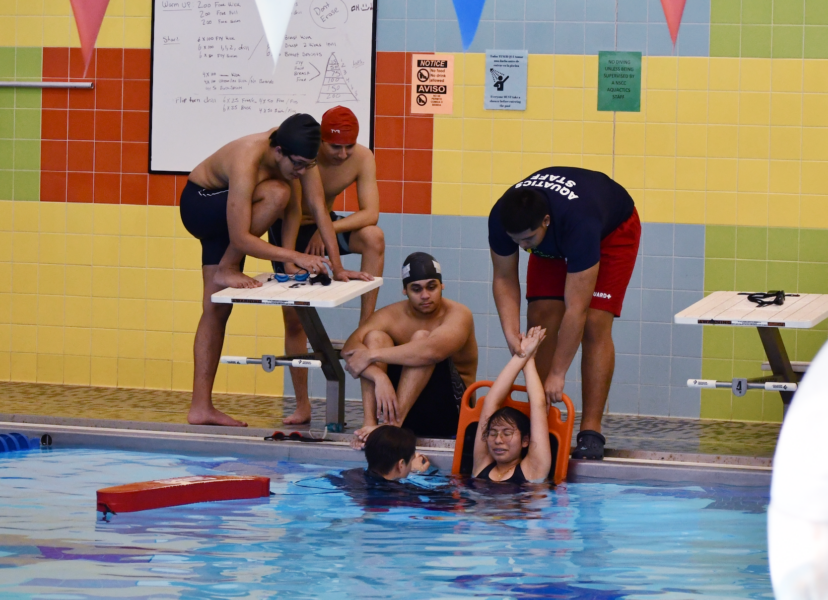 lifeguarding class with five participants doing a backboarding drill